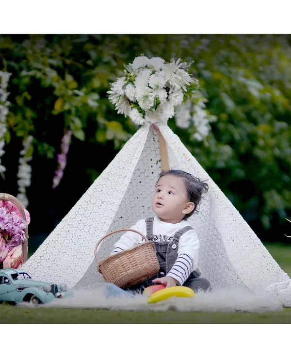 A beautifully composed outdoor kids' photoshoot featuring a toddler in a lace teepee with a basket and vintage toy car. This is an example of our fully styled portrait sessions.