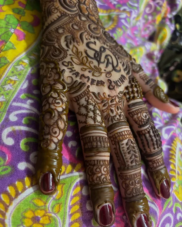 A close up of a personalized bridal henna for Alina, featuring the couple's initials 'S & A' and their names, Shameer and Alina, written below.