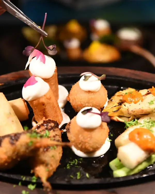A sizzling platter of assorted tapas, featuring croquettes, spring rolls, and other small bites. This is a great way to sample a variety of flavours.