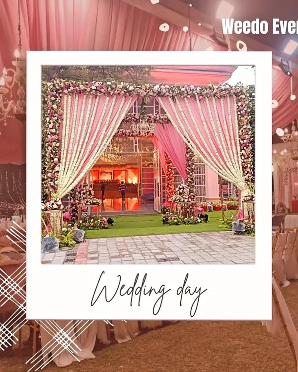 A magnificent entrance for a day wedding, framed like a polaroid. The grand structure is draped in pink fabric with heavy floral borders, creating a picture-perfect welcome.
