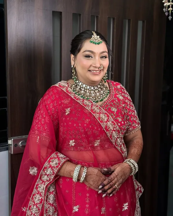 A beautiful, happy bride in a classic red lehenga. I created a soft glam look with defined eyes and a natural, dewy skin finish that complements her emerald jewellery.