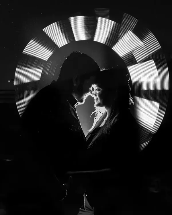 A stunning black and white light painting portrait. By removing the color, we emphasize the silhouette, the light, and the intimate connection between the couple, creating a powerful and artistic image.