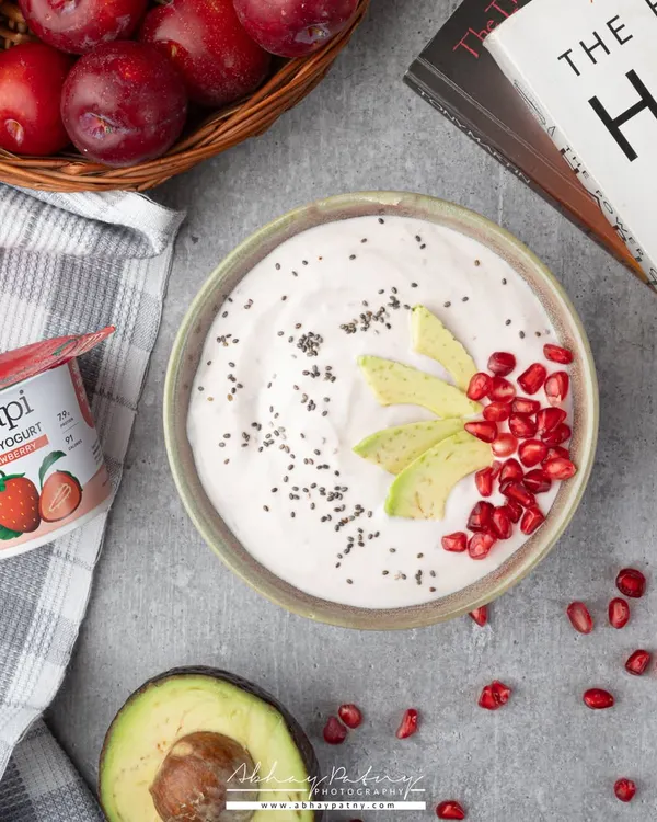 A healthy yogurt bowl styled as part of a wholesome lifestyle. The inclusion of a book and fresh fruits creates a scene of calm, healthy living.
