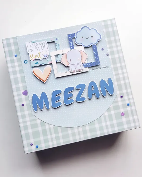 A personalized baby boy scrapbook cover, featuring his name "Meezan" and cute elephant and cloud details. This album comes in a matching gift box.