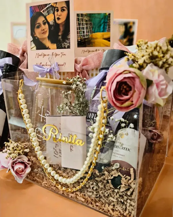 This acrylic bridesmaid hamper is one of my most popular items. It's fully customized with the bridesmaid's name and filled with treats like wine, chocolates, a jade roller, and a personalized tumbler to thank your 'sister' for her support.