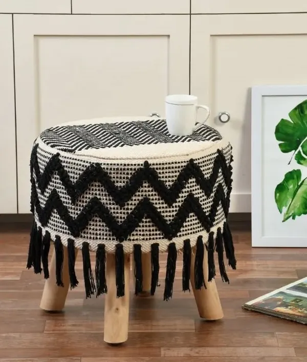 This black and white zig-zag patterned boho stool with fringes is a modern take on bohemian design. It's a versatile piece that works as a seat, footrest, or accent table.
