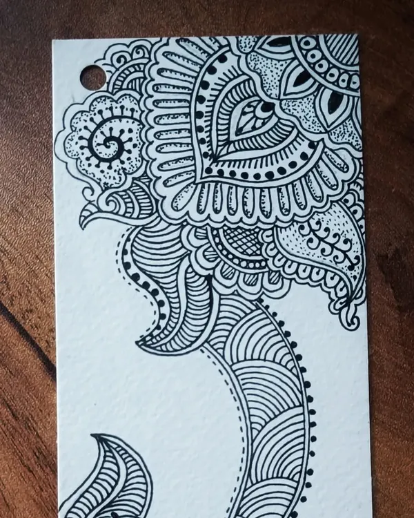 The top half of a hand-drawn bookmark featuring intricate, henna-inspired zentangle patterns made with black pen on paper.