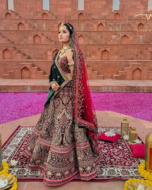 A full view of a majestic bridal lehenga against a stunning backdrop. The deep velvet and detailed embroidery make this a truly royal choice for any bride.