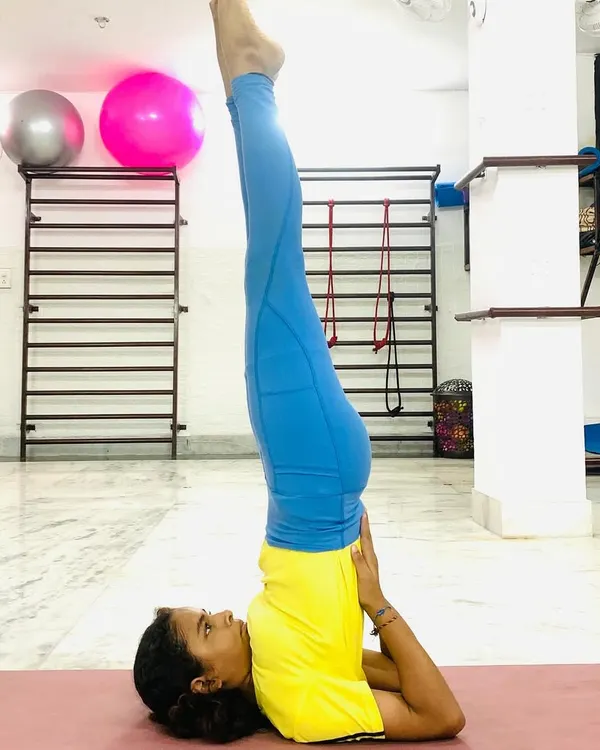 A student holds a perfect Sarvangasana (Shoulder Stand), a pose that improves circulation and calms the nervous system.