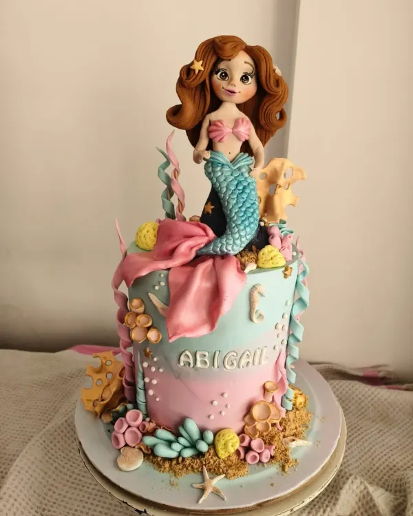 This mermaid cake for Abigail’s first birthday was an underwater dream. The centerpiece is a hand-sculpted mermaid with flowing hair, surrounded by edible coral, seashells, and starfish. The pink and teal ombre effect creates a beautiful ocean backdrop for a magical celebration.