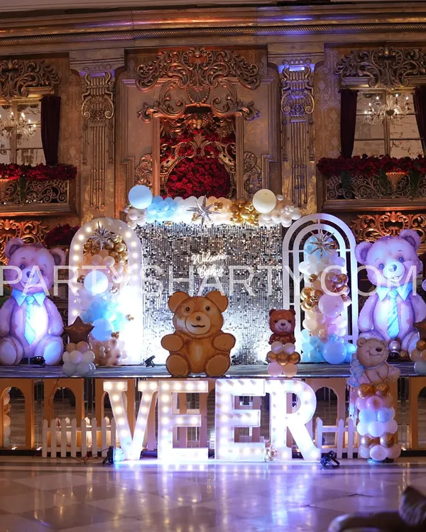 A grand teddy bear stage set against a regal, palace-like wall, featuring large illuminated teddy props and marquee letters for a truly royal feel.