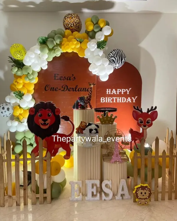 A 'One-Derland' wild jungle theme with a warm, earthy color palette. The setup includes lion and deer cutouts and a custom arch backdrop.