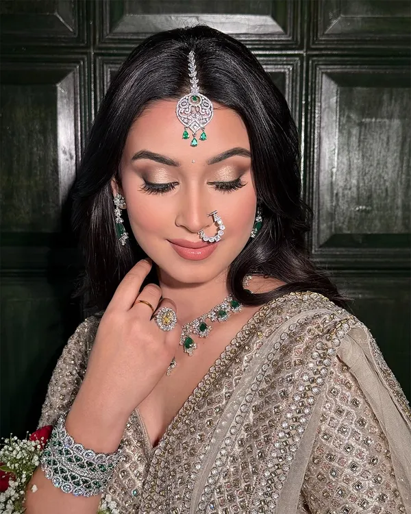 A close-up on the details of this soft glam bridal look. The focus is on the beautifully blended eyeshadow and the flawless base that complements the intricate diamond and emerald jewelry.
