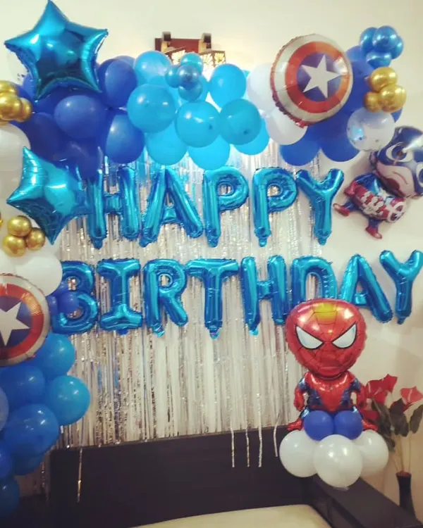 A superhero themed birthday party perfect for a young fan. This bedroom setup includes character balloons like Spiderman and Captain America, star-shaped foils, and a "Happy Birthday" banner in bold blue.