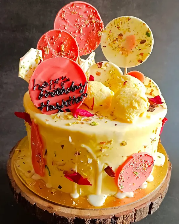 This is my signature Rasmalai Cake, a true bestseller. It features a soft, saffron-infused sponge, creamy frosting, and is topped with homemade rasmalai, pistachios, and decorative chocolate lollipops for a modern, festive look.