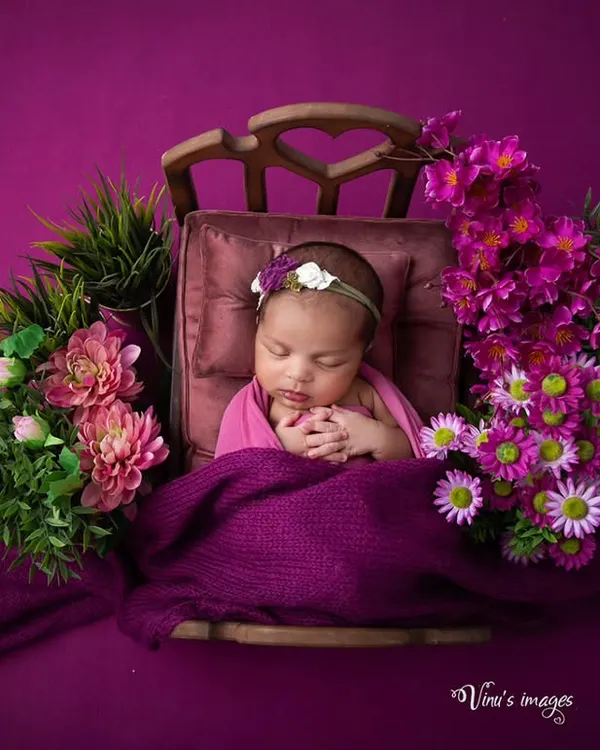 A floral fantasy in shades of purple and pink. This setup features a baby sleeping peacefully in a tiny, ornate bed, surrounded by lush flowers for a rich, artistic portrait.