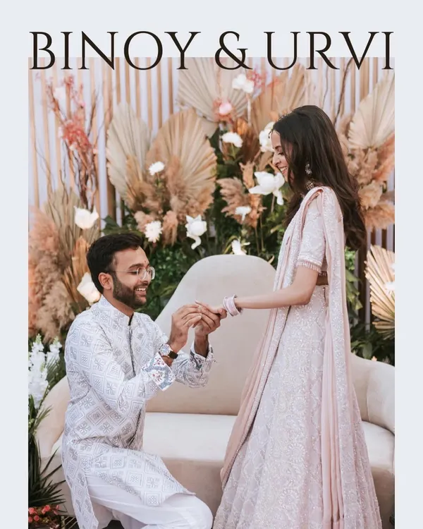 The moment it becomes official. Capturing the ring exchange during an engagement ceremony, with a beautifully decorated backdrop adding to the festive atmosphere.