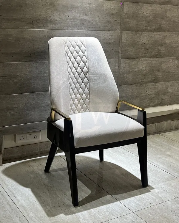 This dining chair is a perfect example of mixed-material design. It features a high back with quilted detailing, a solid wood frame, and elegant metal armrests for a truly luxurious feel.
