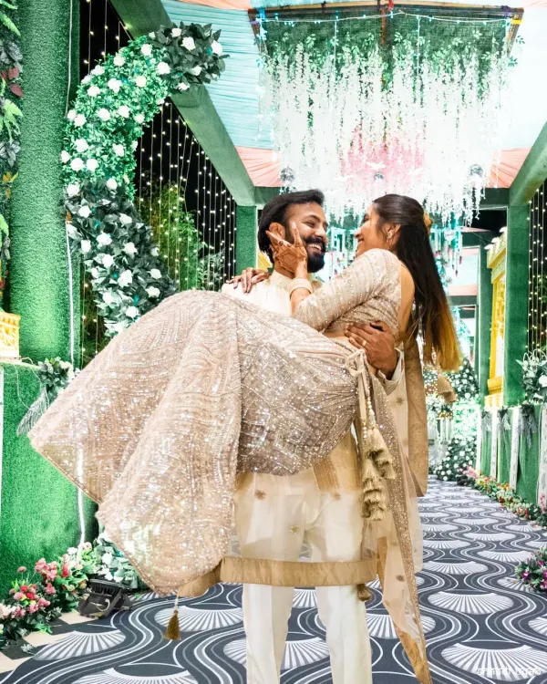 A playful and romantic lift. This kind of shot captures the fun and loving dynamic between the couple, set against the beautiful backdrop of their Sangeet decor.
