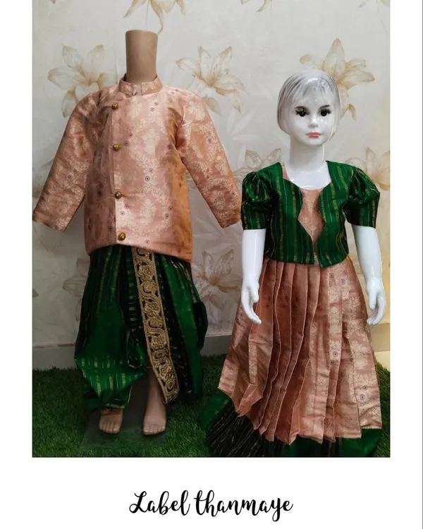 This is a brother and sister ethnic wear set, perfect for festivals or traditional functions. The boy's outfit features a peach Banarasi silk kurta with a green dhoti, complementing the girl's matching Pattu pavadai.