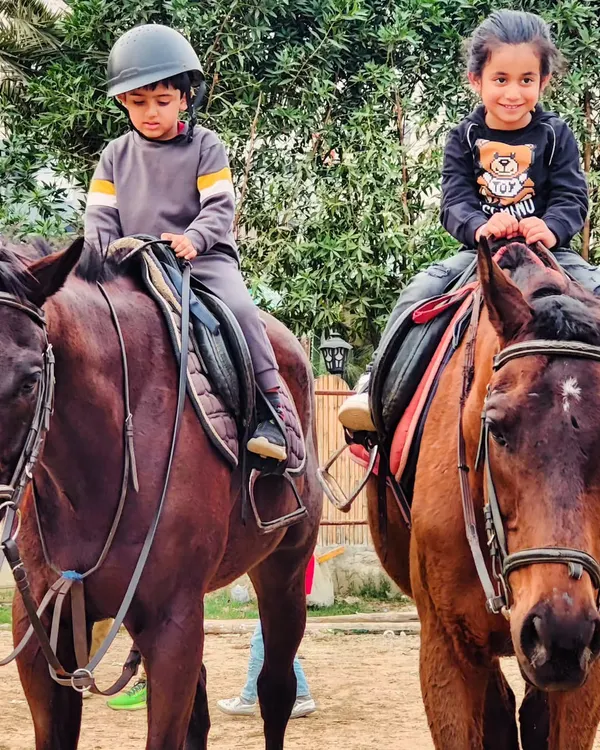 Two young riders sit confidently on their horses, ready for their lesson. We provide well-trained horses suitable for children of all ages and skill levels.