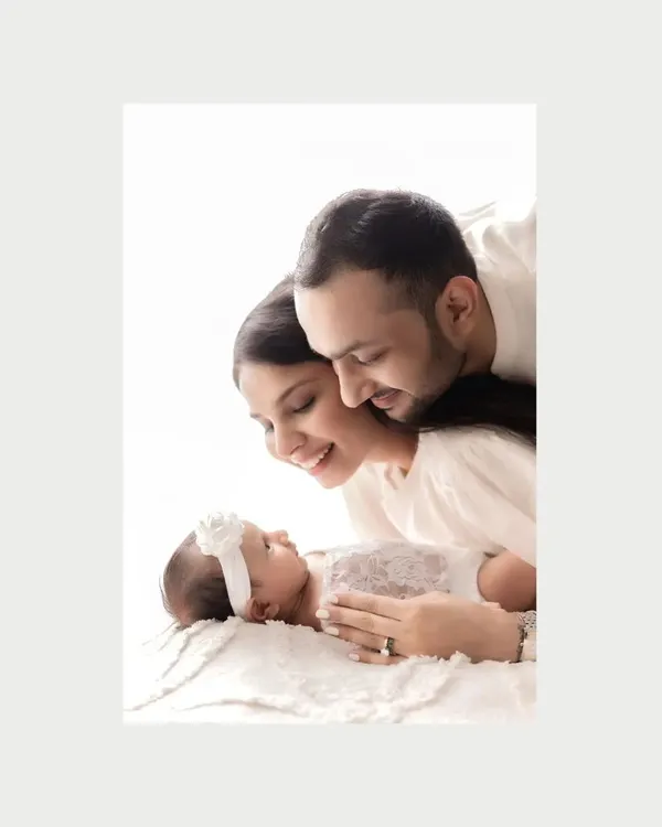 A beautiful color close-up of new parents admiring their sleeping newborn. The soft focus and warm light create an intimate and dreamy portrait, highlighting their love and wonder.