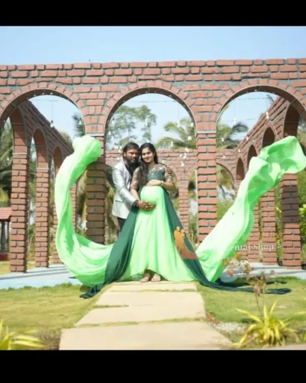 A beautiful couple's maternity portrait featuring our two-tone green flying tail gown. The long, flowing fabric creates a spectacular heart shape, perfectly framing the parents-to-be against a brick archway.