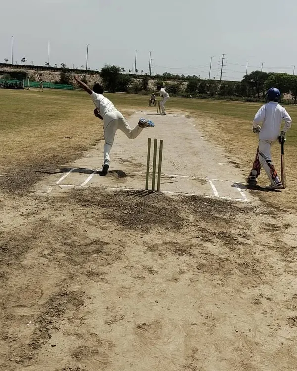 A bowler delivers the ball with full commitment on our turf pitch during a competitive practice match. This kind of high-pressure simulation is key to developing match temperament and tactical awareness for both bowlers and batsmen.