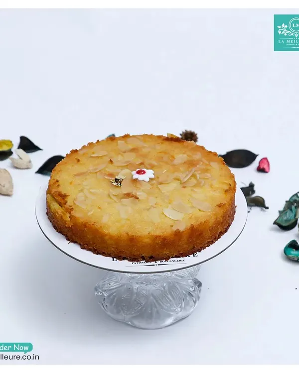 Our Gluten-Free Orange & Almond Tea Cake, presented on a beautiful glass stand. This moist and flavourful cake is a delicious option for everyone to enjoy.