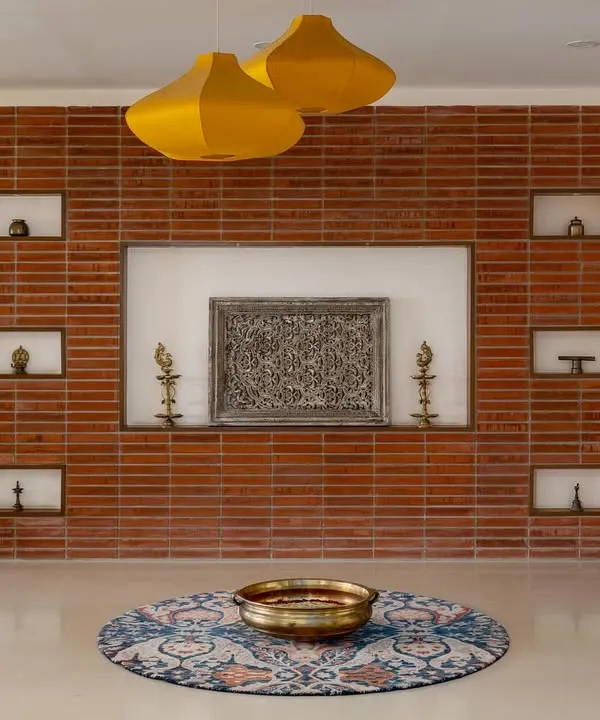 The journey into our 'Vasudhalayah' project begins with this stunning foyer. The wall is cloaked in wire-cut bricks with carved niches for family heirlooms, setting a warm, traditional, and personal tone for the home.