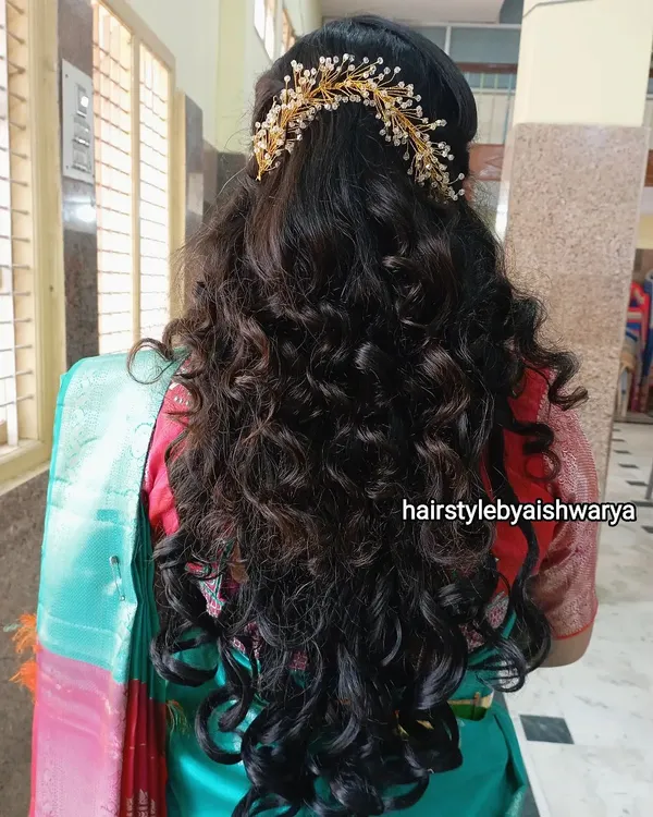Gorgeous, voluminous curls for a naming ceremony. This half-up hairstyle is decorated with a delicate hair accessory, letting the long, bouncy curls flow freely.