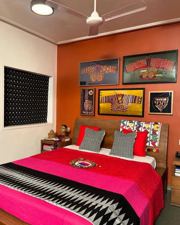 A bedroom makeover featuring my work. The wall displays a gallery of framed vintage ethnic embroidery, while the bed is dressed in a vibrant, hand-quilted throw. Many of these vintage materials are available for custom projects.