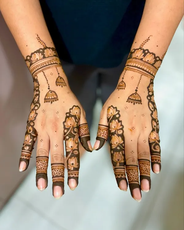 A chic and modern design featuring lotus outlines trailing down the fingers, with delicate jhumka (bell) motifs.