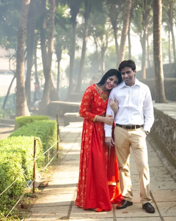 A classic, romantic pose from a pre-wedding shoot in a park. The couple's gentle embrace and the lush green surroundings create a timeless and serene portrait.