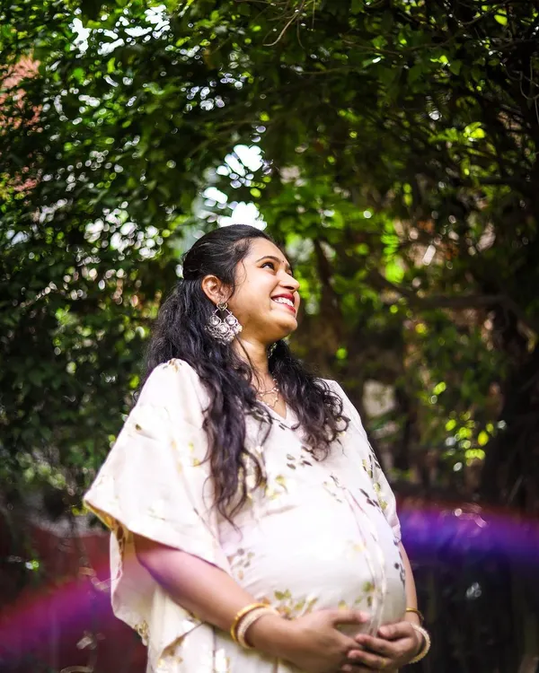 This is a portrait of pure joy. We used the natural garden light and a subtle lens flare to create an artistic, dreamy photo that captures the mother-to-be's happiness and excitement. This style of solo maternity portrait focuses on authentic emotion.