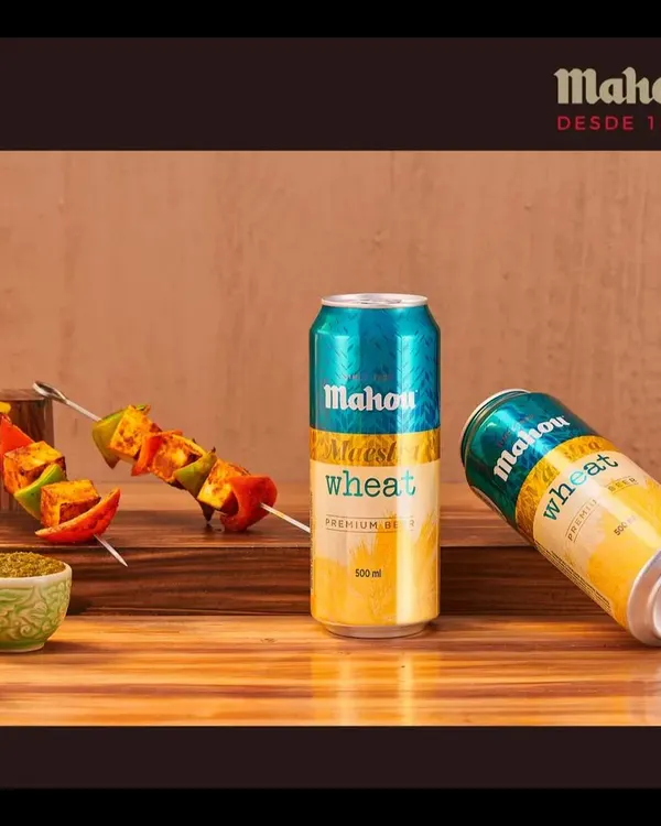 A crisp Mahou Wheat beer paired with vibrant paneer tikka skewers. This shot is designed to create a craving by showcasing the perfect food and drink combination for a social setting.