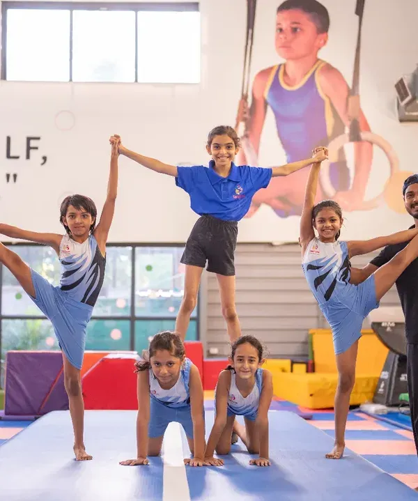 Teamwork makes the dream work. Here, our gymnasts and coaches come together to create a human pyramid, showcasing balance, strength, and the supportive community we build in our kids' fitness classes.