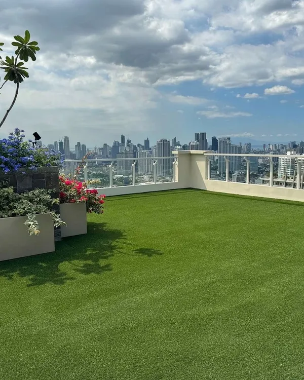 A beautiful rooftop terrace featuring a flawless artificial lawn overlooking the city. This installation provides a consistently green and clean surface, perfect for planters, outdoor furniture, and enjoying the view.