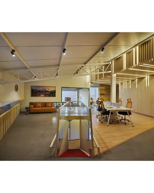 The upper level of the Kadence Office, showing the open-plan workspace and lounge area. The design preserves the building's original industrial trusses while introducing a mezzanine and our custom "soundwave" wall, creating a layered and dynamic environment.