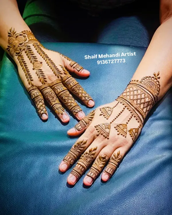 A chic and modern back-of-hand design. One hand features hanging jhumka (bell) motifs, while the other has a leafy vine pattern, showing how you can mix and match minimalist styles.
