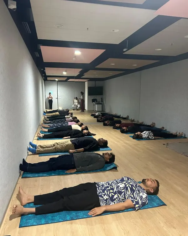 Employees of a company resting during a corporate wellness session. Providing a space for teams to lie down and receive a sound bath is an effective way to combat collective stress and burnout.