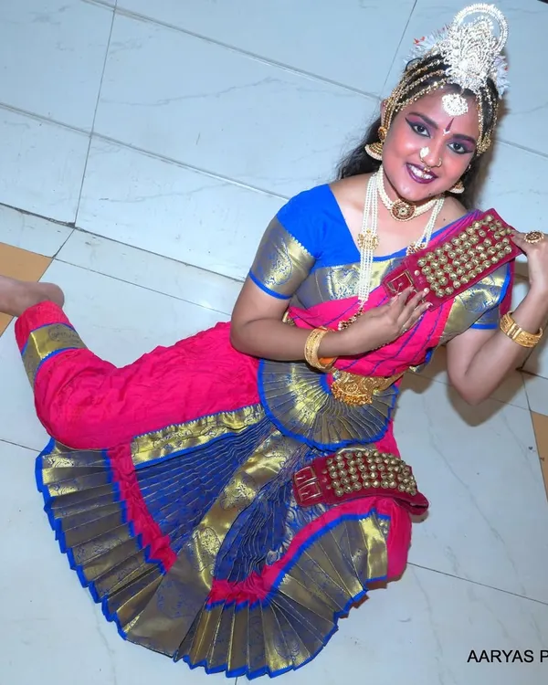 A dynamic, high-angle shot of a Bharatanatyam dancer in a traditional pose. This perspective highlights the beautiful flare of the costume and the dancer's graceful form.
