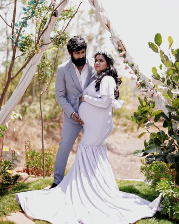 An angelic maternity look for an outdoor shoot. This expecting mother is styled in a white mermaid gown with delicate shoulder bows, creating a soft and serene portrait.