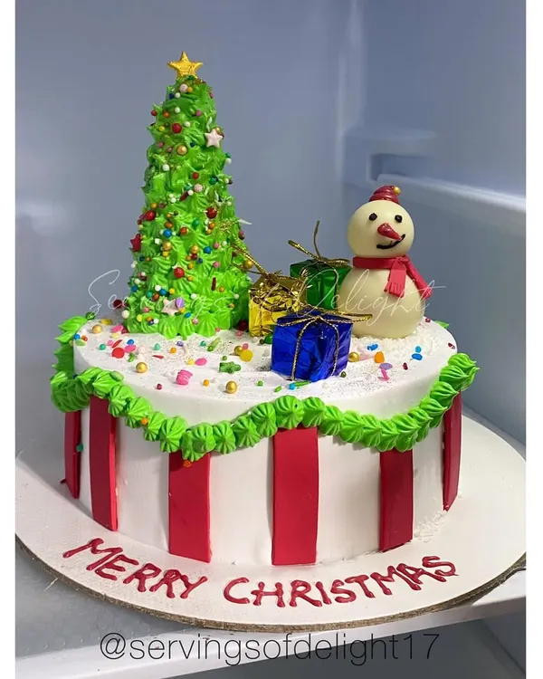My Merry Christmas cake. This festive creation features a buttercream Christmas tree, a cute snowman, and edible presents.