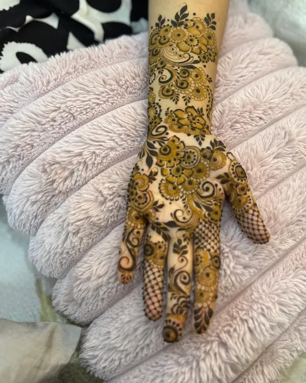 An intricate floral design on the back of the hand, with delicate vines and checkerboard patterns on the fingers.