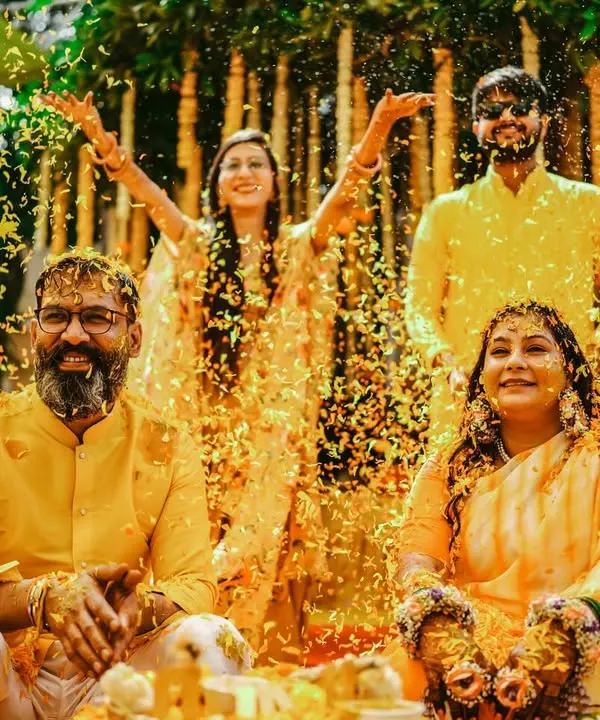 A perfect family moment at the Haldi ceremony. The couple is showered with marigold petals by their loved ones, creating a vibrant and joyous scene filled with laughter and blessings.