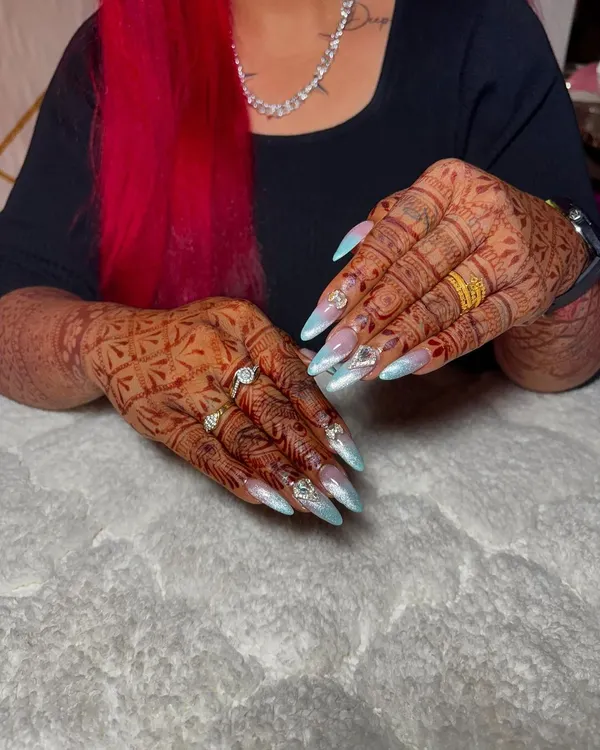 The ultimate bridal nails. These long, stiletto extensions feature a soft blue and white ombre, adorned with crystals and designed to complement intricate henna.