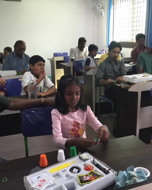 Here you can see the fun in action. Students, both young and old, are getting hands-on with their personal magic kits, practicing the cups and balls trick. This is what my workshops are all about: interactive learning for everyone.