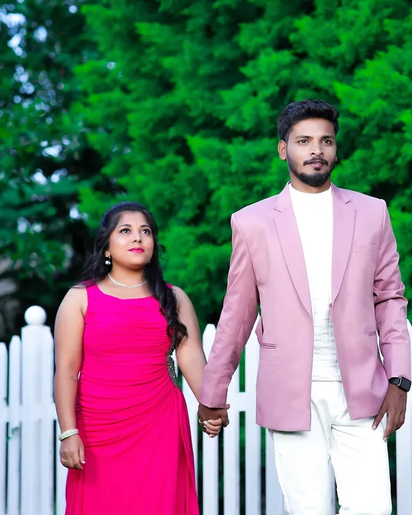 One step closer to forever. This couple looks lovely in their coordinated outfits for a pre-wedding shoot. She is in a flowing pink gown, and he is in a matching pink blazer with white trousers.