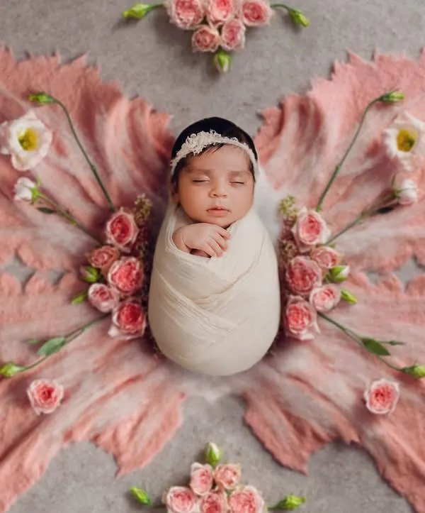 This is the art of newborn photography. A peacefully sleeping baby, styled as a delicate butterfly with soft pink fabric and fresh flowers, shows how I turn a simple portrait into a timeless piece of art. These posed newborn sessions are my specialty.